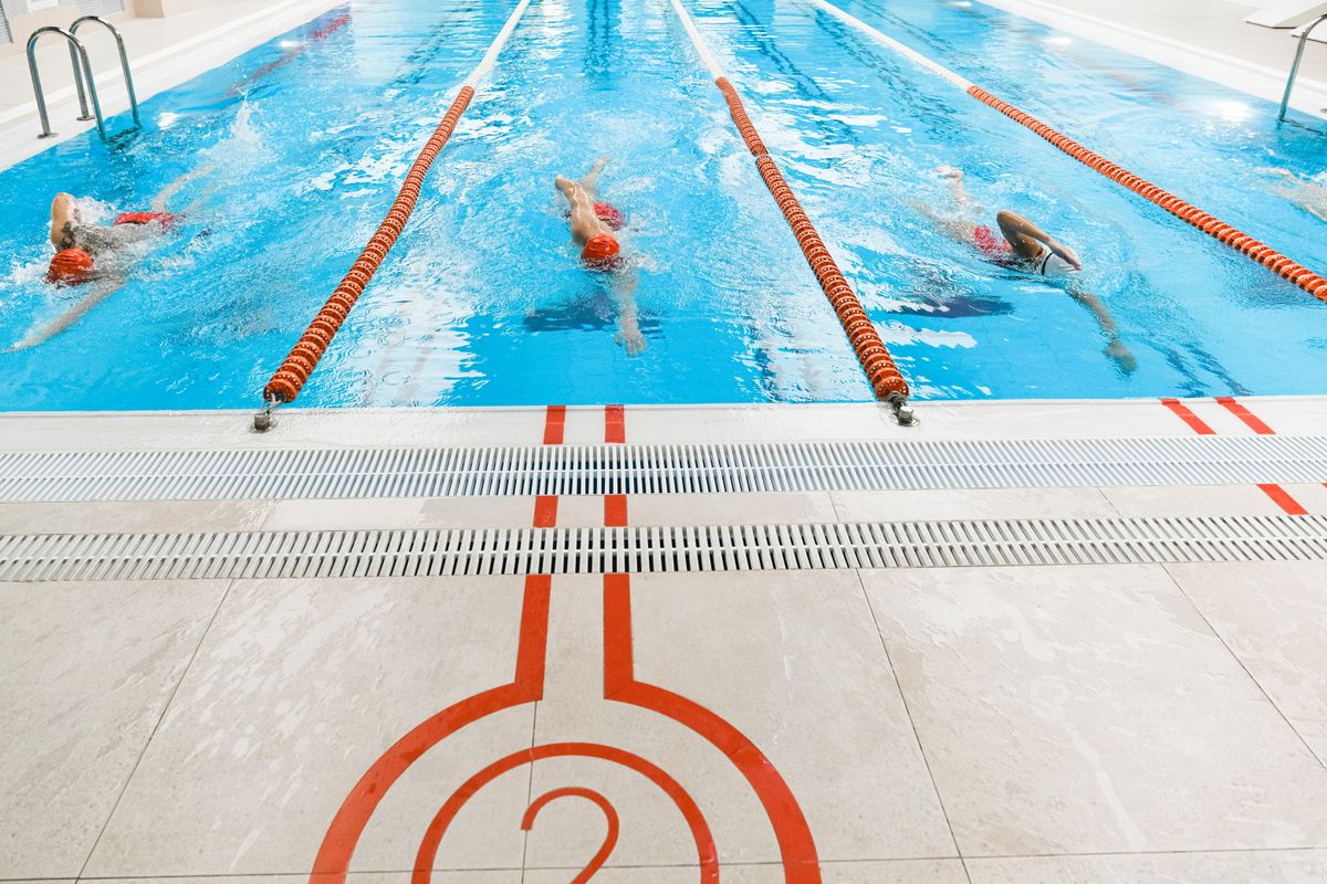Nuotatori che si allenano a stile libero nelle corsie di una piscina coperta
