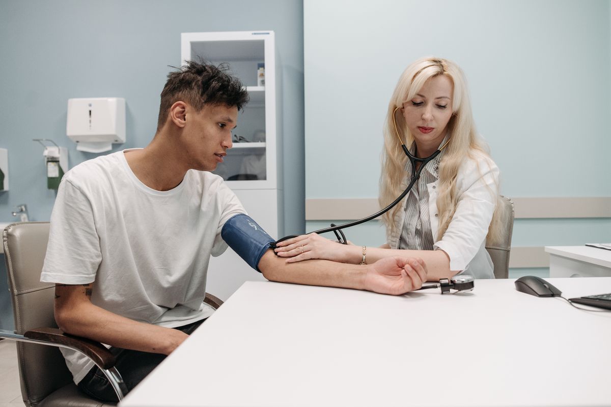Medica che misura la pressione arteriosa a un paziente durante una visita